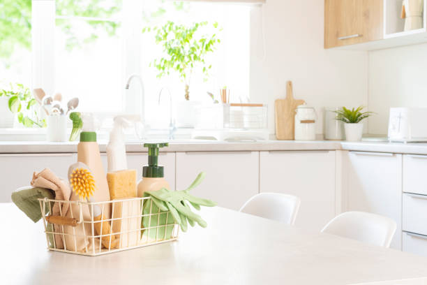 Various eco cleaning products in basket on table with blurred kitchen interior as background