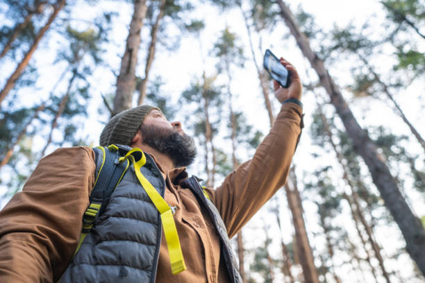 istock A man with a backpack in the forest tries to catch a cellular signal from a smartphone, low angle view 2153345433