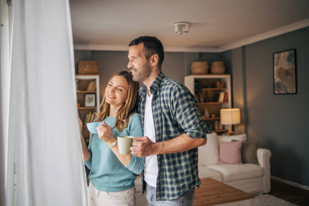 istock Young couple looking through the window in their home 2153348303