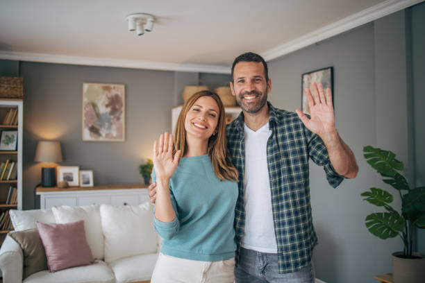 istock Cheerful couple waving while looking at camera and smiling 2153348409