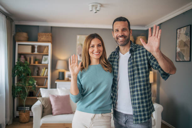 istock Cheerful couple waving while looking at camera and smiling 2153348412