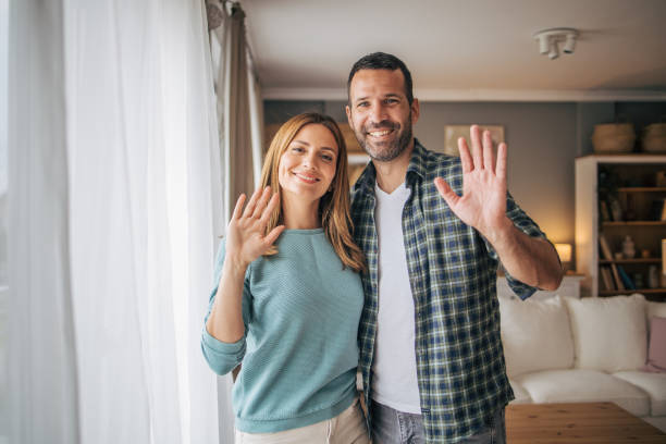 istock Cheerful couple waving while looking at camera and smiling 2153348413