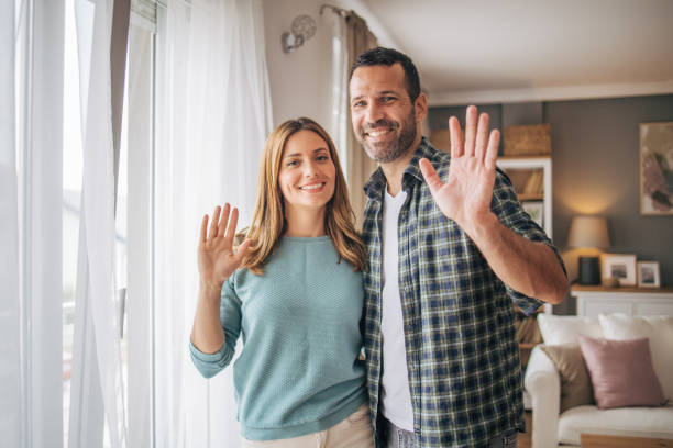 istock Cheerful couple waving while looking at camera and smiling 2153348450
