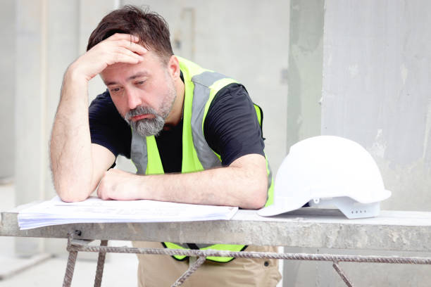 istock Panic senior worker engineer foreman with safety vest and helmet put hand on head while staring at blueprint at construction site. Stressed worried elderly architect works at building site workplace. 2153350172