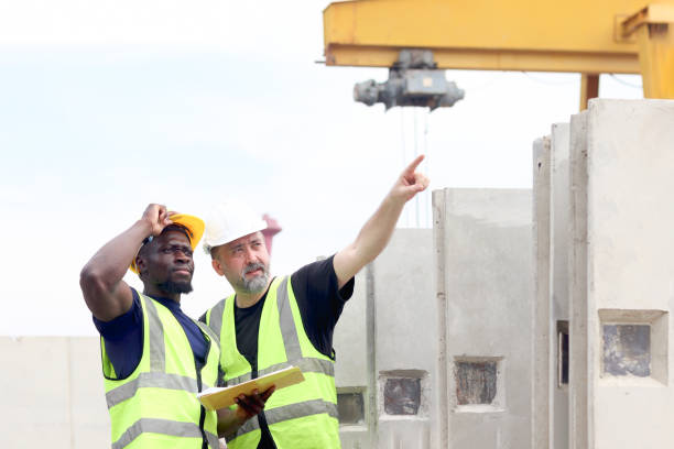 istock Harmony diversity people at workplace, senior elderly foreman and African engineer inspecting and pointing towards an area of construction site. Architects working at building site workplace. 2153350266