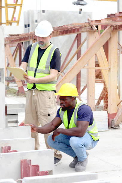istock Harmony diversity people at workplace, senior foreman and African engineer holding document file to inspection at construction site at construction site. Workers working together at building site. 2153350294