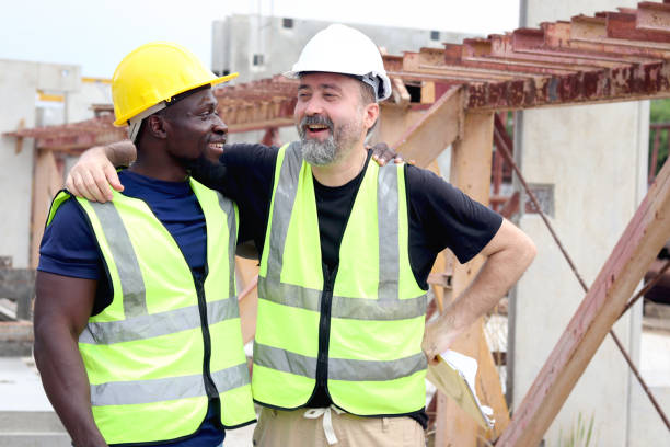 istock Happy harmony people at workplace, smiling white foreman and African engineer worker cuddle around necks at construction building site. Love and respect in differences of race skin color, diversity 2153350314