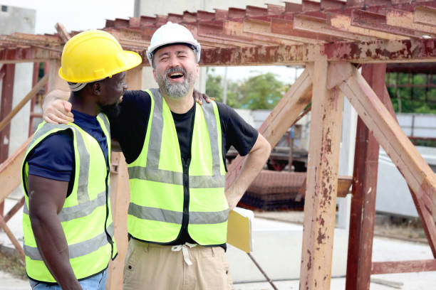 istock Happy harmony people at workplace, smiling white foreman and African engineer worker cuddle around necks at construction building site. Love and respect in differences of race skin color, diversity 2153350381