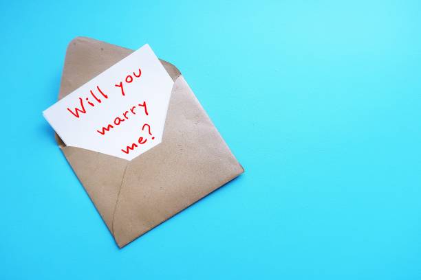 istock On blue copy space background, envelope with card written WILL YOU MARRY ME?  a simple standard marriage proposal when someone pop a question to the one they love 2153353552