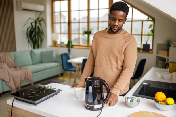 istock Young man using an electric kettle to make tea at home 2153356482