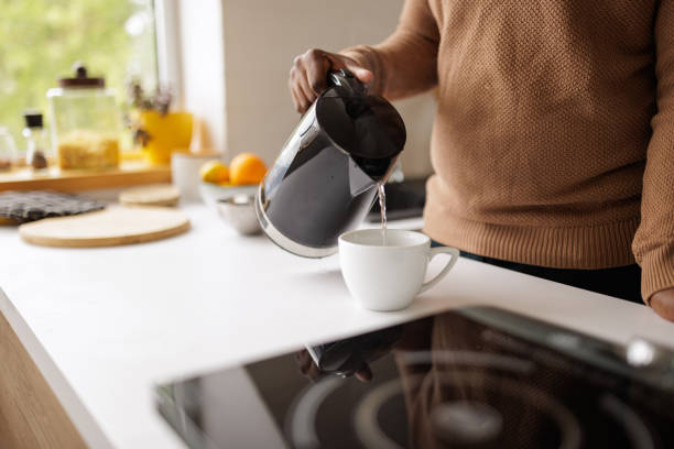 istock Young man using an electric kettle to make tea at home 2153356575
