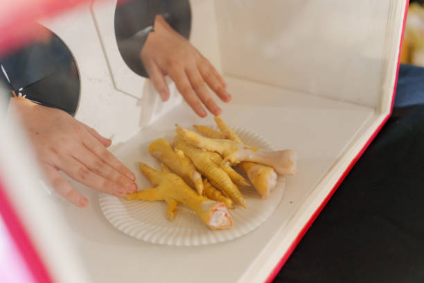istock hands touch Chicken feet in a box behind the glass. hoax. 2153357310