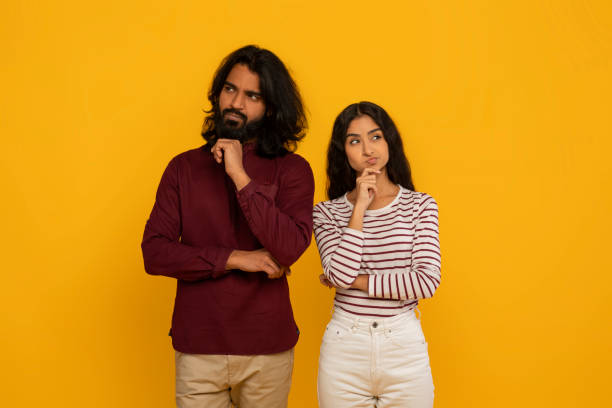 istock Thoughtful couple with pensive expressions on yellow 2153361068