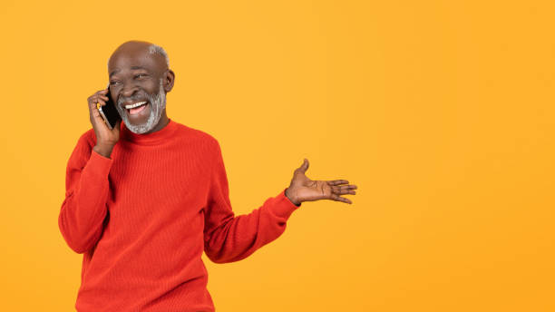istock Happy senior black man in red sweater talking on the phone with a delighted expression 2153363450