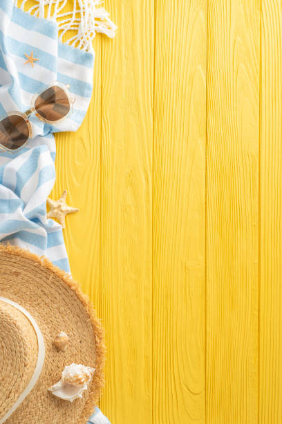 istock Seaside allure depicted: Top-view vertical composition showcasing sunhat, sunglasses, island trinkets, blanket, shells, starfish on sunny wooden surface, offering area for text or promotional messages 2153365245