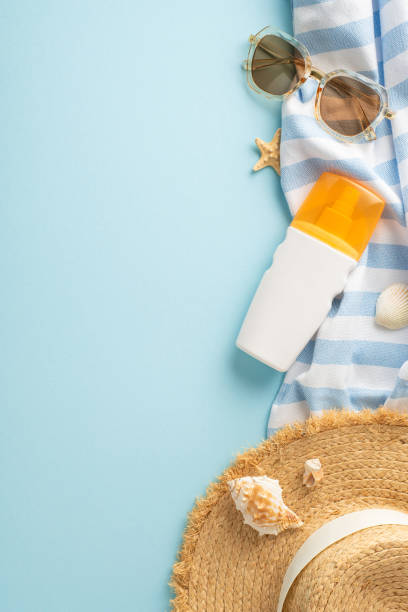 istock Overhead vertical shot showcasing SPF cream, straw hat, shades, beach essentials, and tropical vibes on a pastel blue surface, perfect for text or promotional content 2153365279