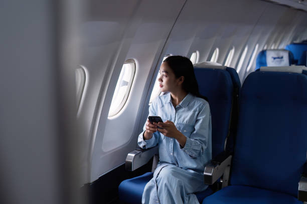 istock Asian people female person onboard, airplane window, using mobile while on the plane 2153365284