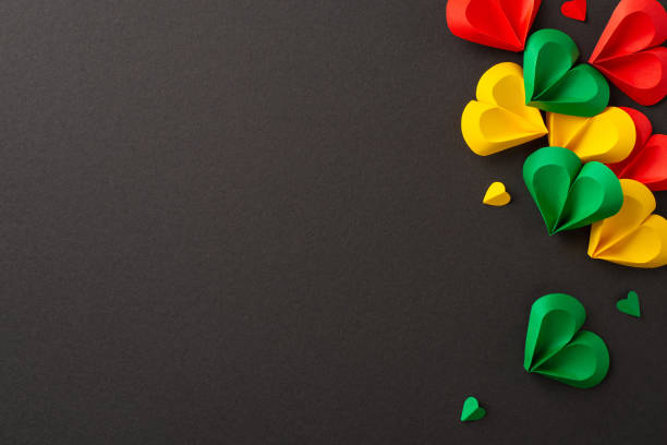 istock Liberation observance: hearts in red, green, yellow on black canvas, symbolizing Juneteenth's end of slavery. Overhead perspective permits social text or ad inclusion 2153365302
