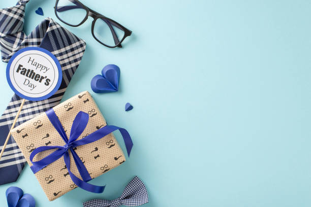 istock Stylish Father's Day celebration setup featuring a gift box, bow tie, glasses, and a greeting card on a pastel blue background 2153365374