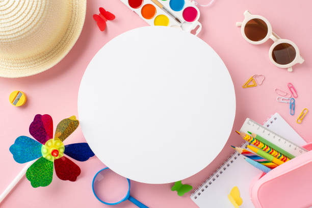 Pre-K summer learning concept. Top view of creativity gear - sketchbook, colored pencils, paint set, outdoor items - sunhat, sunglasses, wind toy, butterflies on soft pink background with empty circle concepto de aprendizaje de verano de pre-k. vista superior del equipo de creatividad: cuaderno de bocetos, lápices de colores, juego de pintura, artículos al aire libre: sombrero para el sol, gafas de sol, juguete de viento, mariposas sobre fondo rosa su