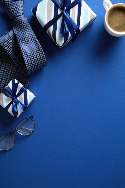 istock Flat lay composition featuring a gift, neckties, eyeglasses, and a cup of coffee on a vibrant blue background. Ideal for themes related to business, gifting, or celebration. 2153367029