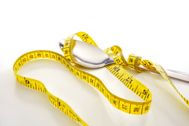 Silver fork with measuring tape together placed on white background close up view selective focused food concept photography