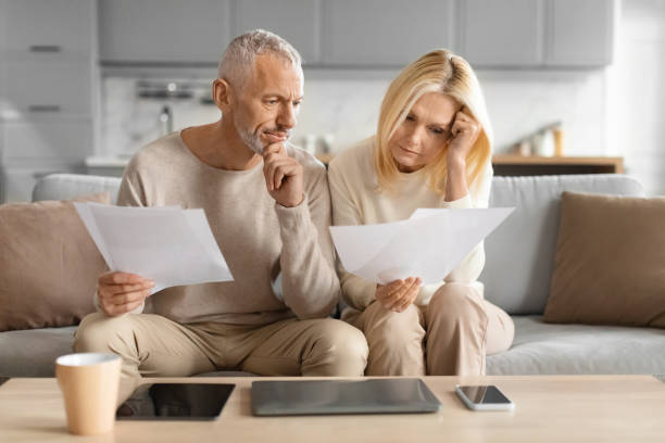istock Concerned couple reviewing papers with serious faces 2153371019