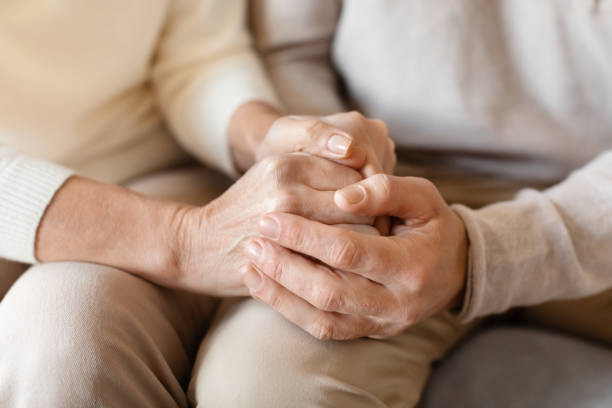 istock Old middle aged people holding hands close up view 2153371040