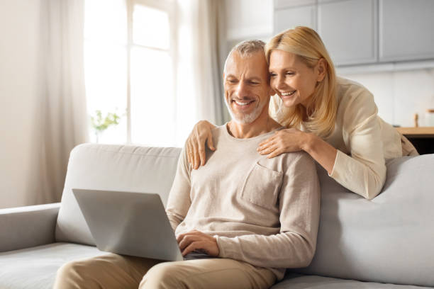 istock Positive beautiful loving senior spouses using laptop at home 2153371061