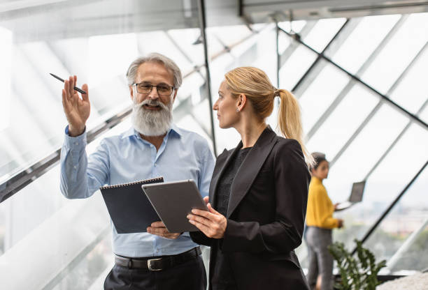 istock Senior Executive and Female Colleague Collaborate on Tablet 2153372235