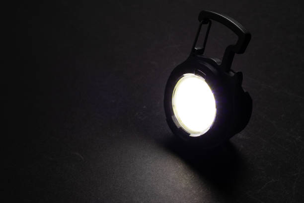 istock LED Flashlight Keychain and a beam of light in darkness. A modern led lamp with bright projection on dark table. 2153381397