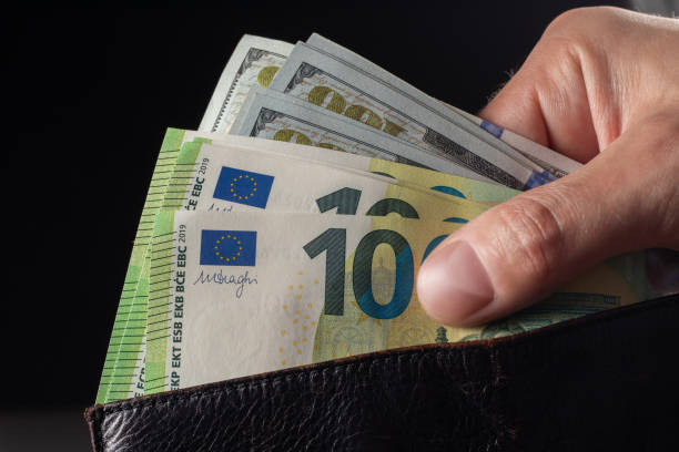 istock Man handing wallet with 100 euro and 100 dollars banknotes 2153381423