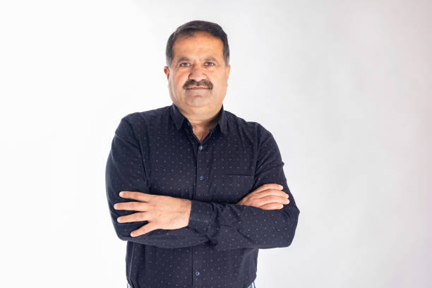 istock Happy mature man with arms crossed and looking at camera while standing against white background 2153382337