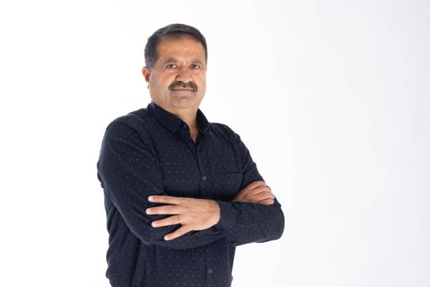 istock Happy mature man with arms crossed and looking at camera while standing against white background 2153382345
