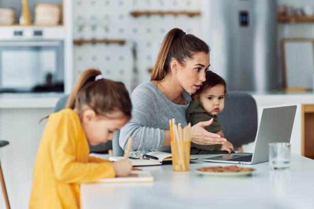 istock A busy working mother having a work-related video call at home on her laptop and looking after her children 2153382559