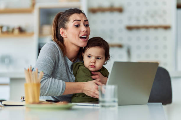 istock A working mother holding her toddler in her lap while having a video conference call on her laptop 2153382578