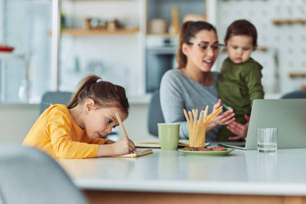 istock A creative little girl drawing in her notebook while her mother is working from home in the background 2153382612