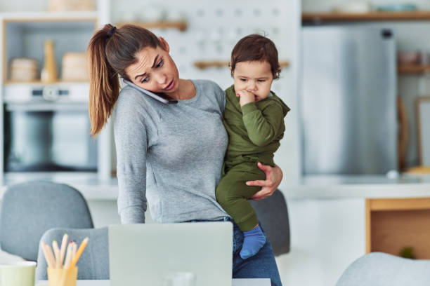 istock A busy mother multitasking and working from home while talking on a phone and carrying her small child 2153382642