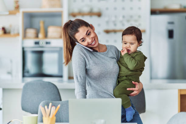 istock A smiling mother having a phone call and working from home while holding her toddler 2153382652