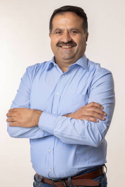 istock Happy mature man with arms crossed and looking at camera while standing against white background 2153385611