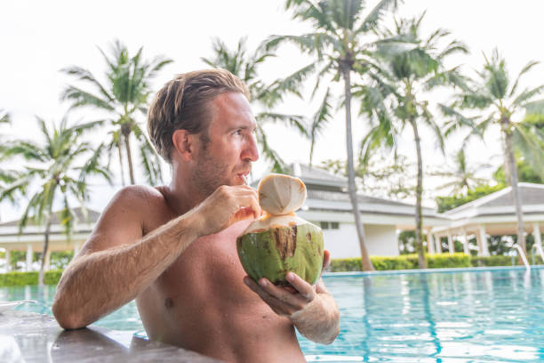 istock Man Sipping Fresh Coconut Drink at Poolside 2153386178