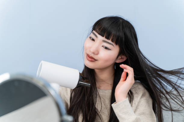 istock young woman using a hair dryer 2153386535