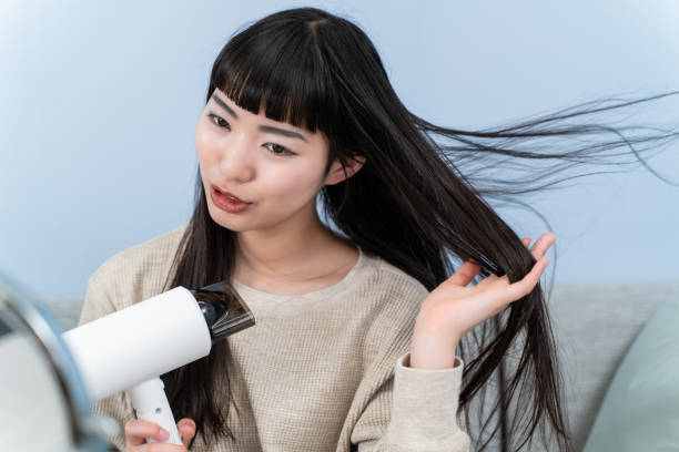 istock young woman using a hair dryer 2153386585