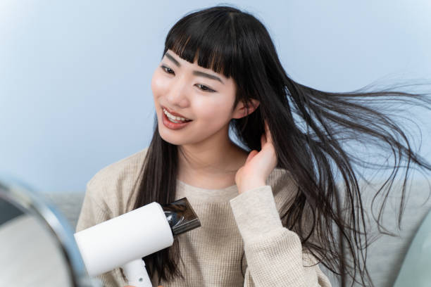 istock young woman using a hair dryer 2153387244