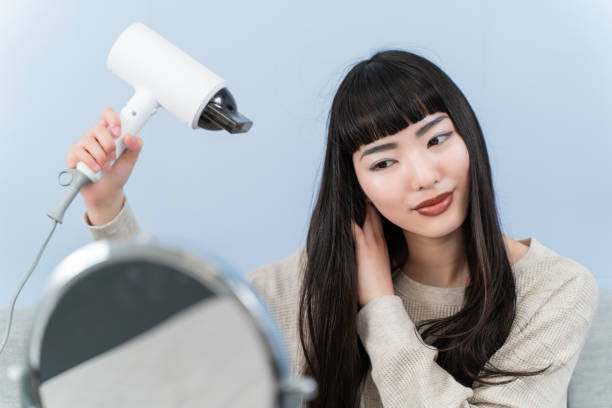 istock young woman using a hair dryer 2153387478