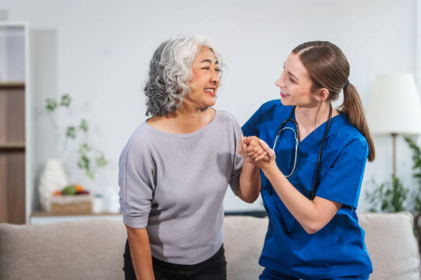 istock Caucasian female doctor assists in supporting an elderly Asian patient while they both sit on the sofa, ensuring comfort and stability during the interaction. 2153391018