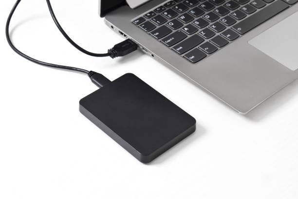 istock External backup hard disk drive connected to laptop on white background 2153404216