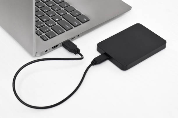 istock External backup hard disk drive connected to laptop on white background 2153404242