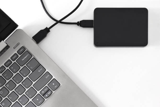 istock External backup hard disk drive connected to laptop on white background 2153404849