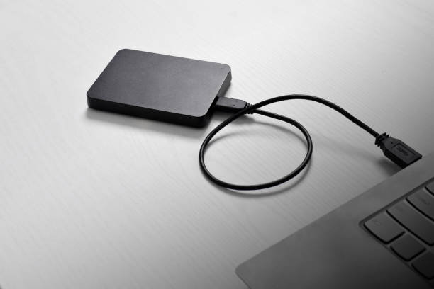 istock External backup hard disk drive connected to laptop on white background 2153404850